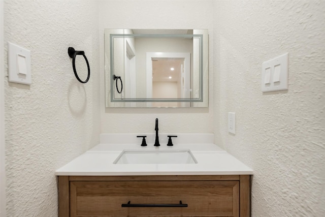 bathroom with a textured wall and vanity