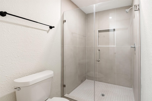 full bathroom featuring a stall shower, a textured wall, and toilet