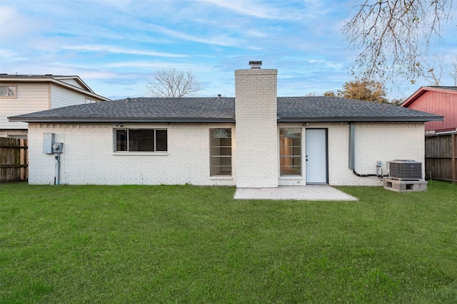 rear view of property featuring brick siding, fence, a chimney, and a lawn