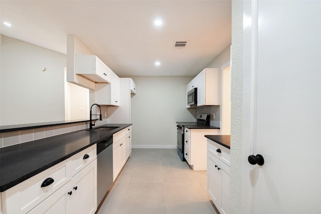 kitchen with stainless steel appliances, dark countertops, tasteful backsplash, visible vents, and a sink