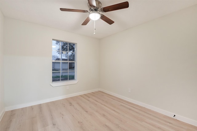 spare room featuring light wood-type flooring, a ceiling fan, and baseboards