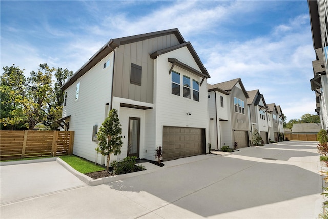 exterior space featuring board and batten siding, fence, a garage, a residential view, and driveway