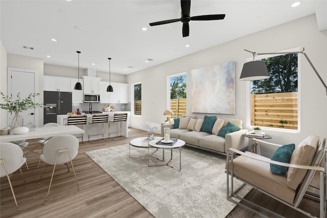 living room featuring a ceiling fan, recessed lighting, visible vents, and light wood-style floors