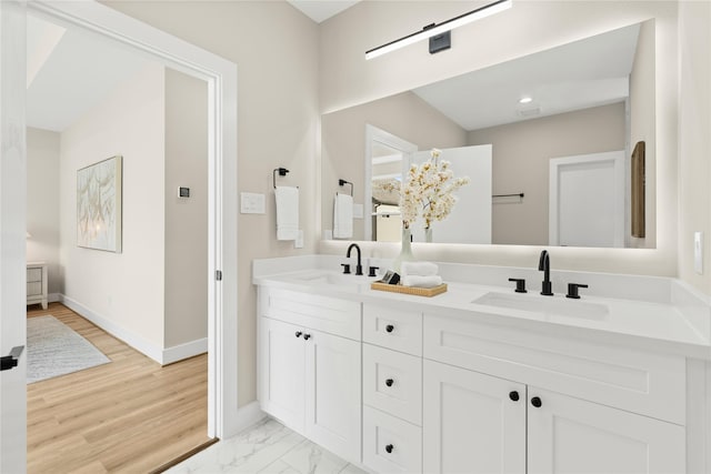 full bathroom featuring marble finish floor, double vanity, a sink, and baseboards