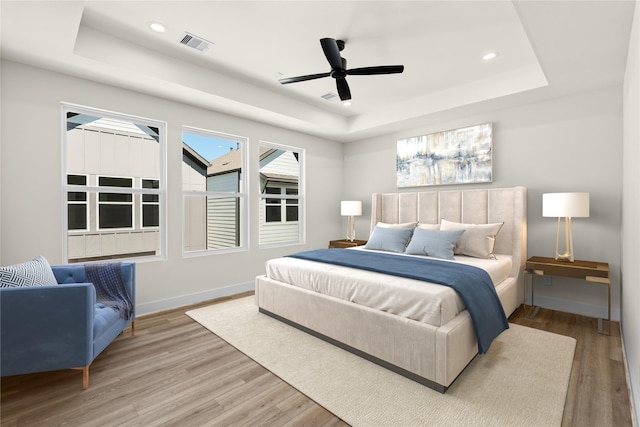 bedroom featuring wood finished floors, a raised ceiling, and visible vents