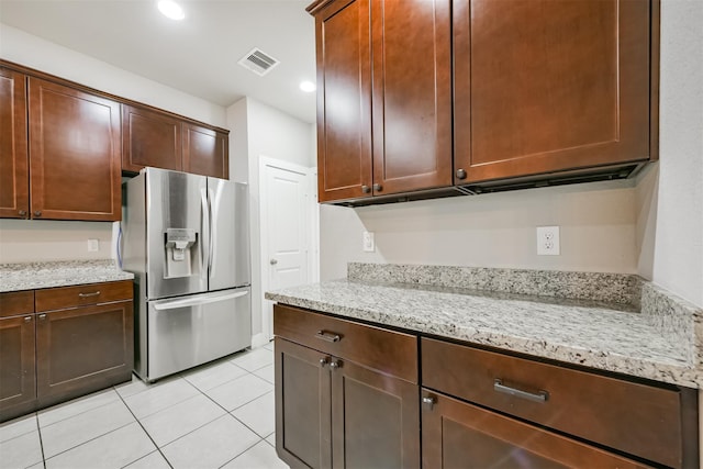 kitchen featuring recessed lighting, light tile patterned flooring, stainless steel fridge, and light stone countertops