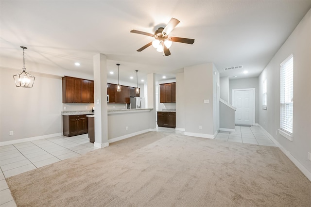 unfurnished living room with ceiling fan, light tile patterned flooring, light carpet, visible vents, and baseboards