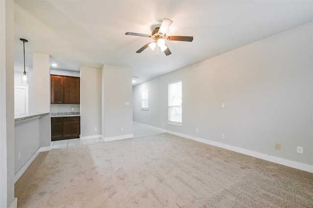 unfurnished living room featuring light colored carpet, ceiling fan, and baseboards