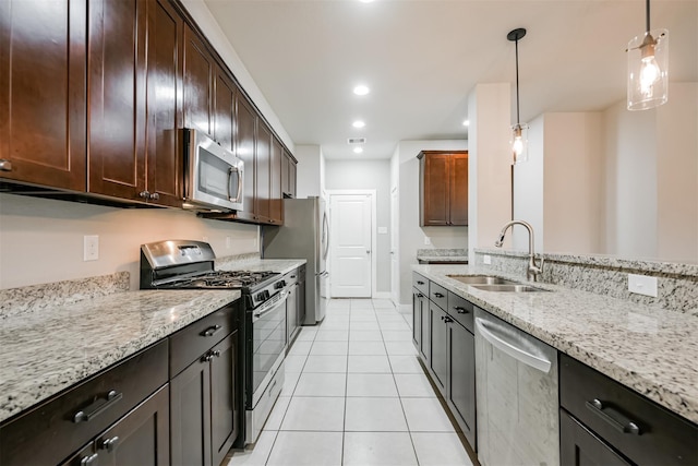 kitchen featuring light tile patterned floors, appliances with stainless steel finishes, light stone countertops, pendant lighting, and a sink