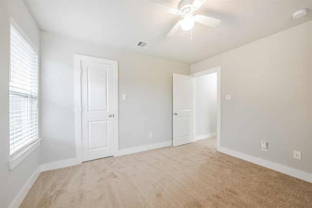 unfurnished bedroom featuring visible vents, light carpet, baseboards, and multiple windows