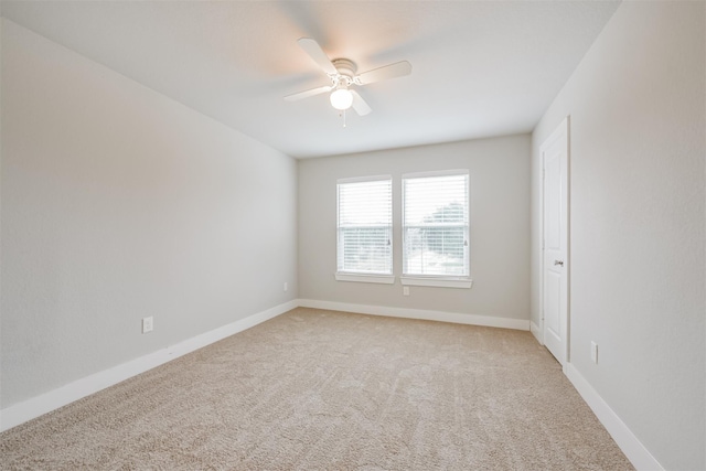 spare room featuring light carpet, ceiling fan, and baseboards