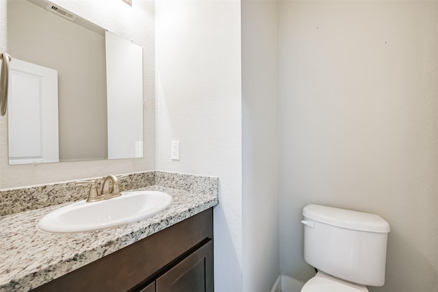 half bath with toilet, visible vents, and vanity