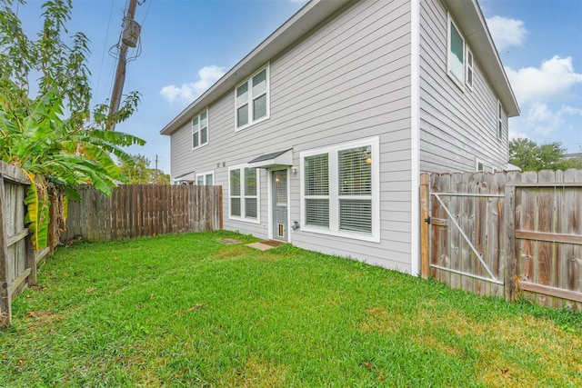 back of house with a fenced backyard and a lawn