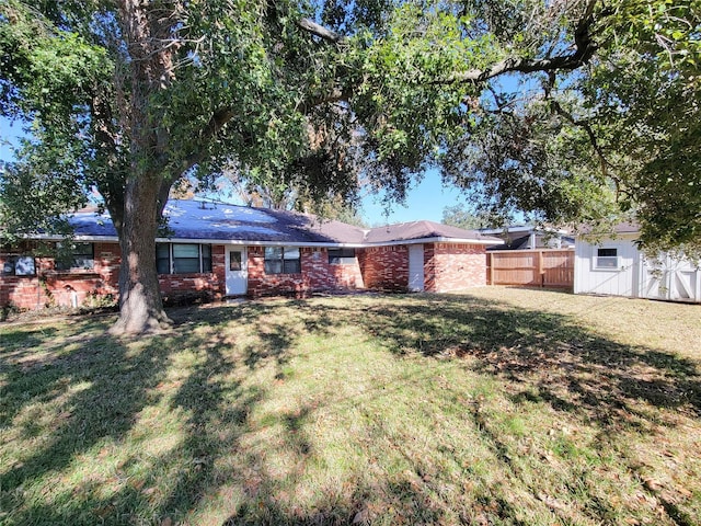 exterior space with a front yard, fence, an outdoor structure, and brick siding