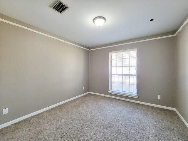 spare room featuring crown molding, carpet floors, visible vents, and baseboards