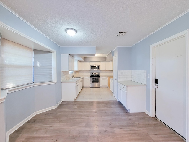 kitchen with light wood-type flooring, decorative backsplash, stainless steel appliances, and a sink