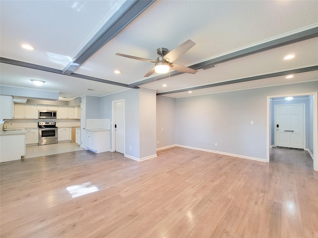 unfurnished living room featuring light wood-style floors, a ceiling fan, visible vents, and beam ceiling