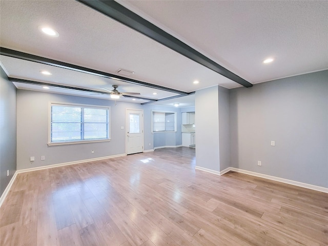 unfurnished living room with beam ceiling, light wood finished floors, ceiling fan, a textured ceiling, and baseboards