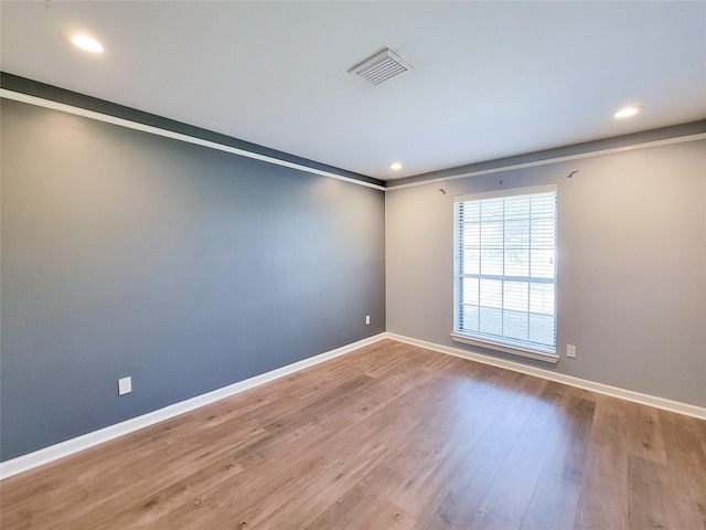 unfurnished room featuring recessed lighting, wood finished floors, visible vents, and baseboards