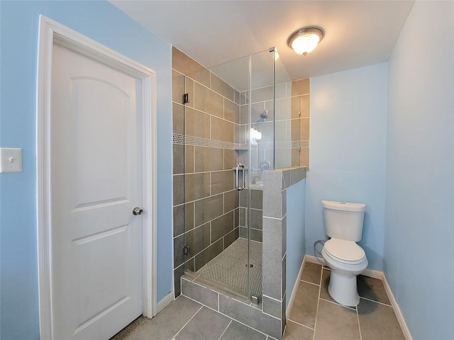 bathroom with toilet, a shower stall, baseboards, and tile patterned floors