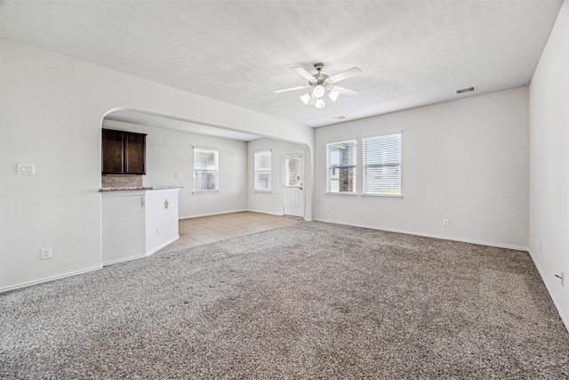 unfurnished living room with light carpet, baseboards, visible vents, a ceiling fan, and a textured ceiling