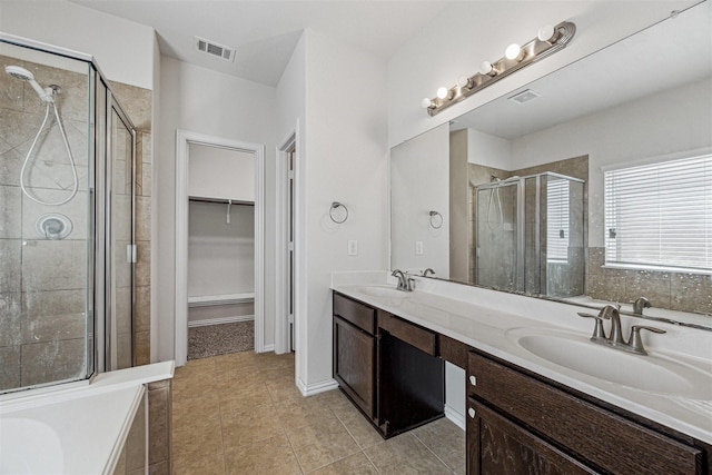 bathroom featuring a spacious closet, a stall shower, a sink, and visible vents