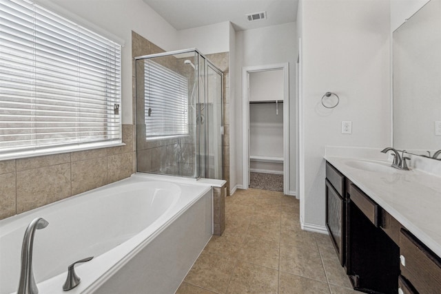 full bathroom featuring a stall shower, a walk in closet, a bath, and tile patterned floors