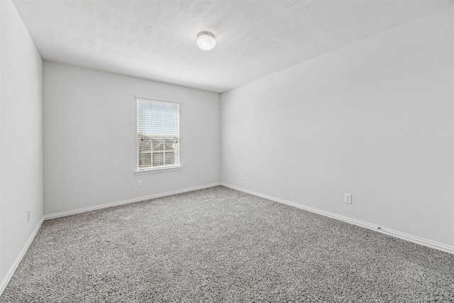 unfurnished room featuring carpet floors, a textured ceiling, and baseboards