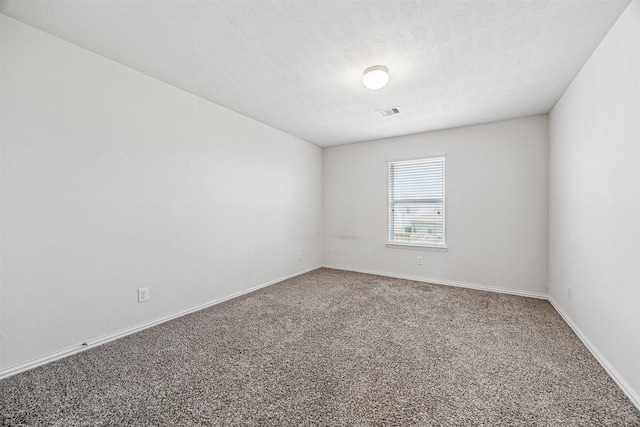 carpeted spare room with a textured ceiling, visible vents, and baseboards