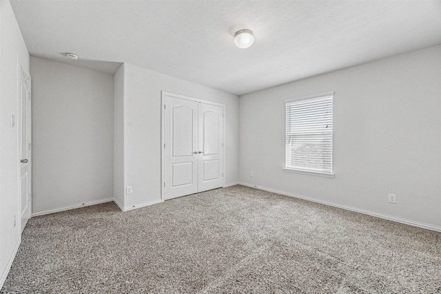 unfurnished bedroom featuring a closet, baseboards, and carpet flooring