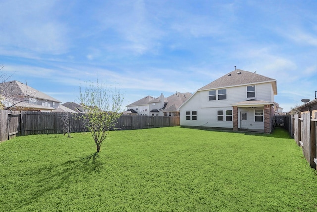 back of house with brick siding, a fenced backyard, roof with shingles, and a yard