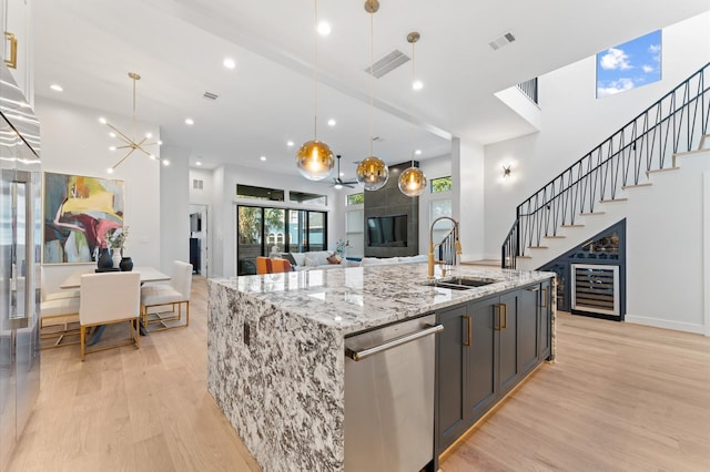 kitchen with visible vents, light wood finished floors, a sink, wine cooler, and stainless steel dishwasher