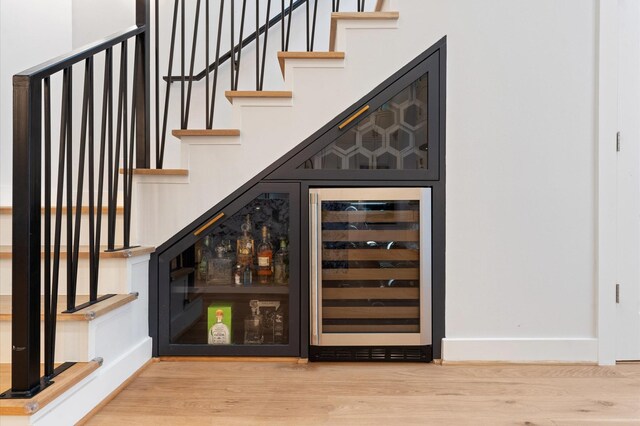 bar with baseboards, wine cooler, wood finished floors, and a dry bar