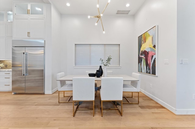 dining room with light wood-type flooring, baseboards, a notable chandelier, and visible vents