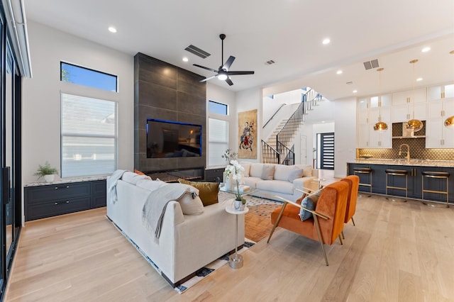 living area featuring visible vents, light wood-style flooring, and stairway