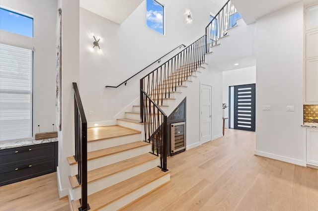 staircase with a high ceiling, wood finished floors, and baseboards