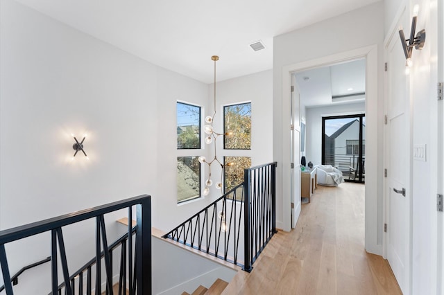 corridor with an upstairs landing, light wood-type flooring, and baseboards