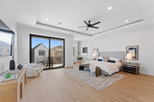 bedroom featuring a raised ceiling, access to exterior, visible vents, and light wood finished floors