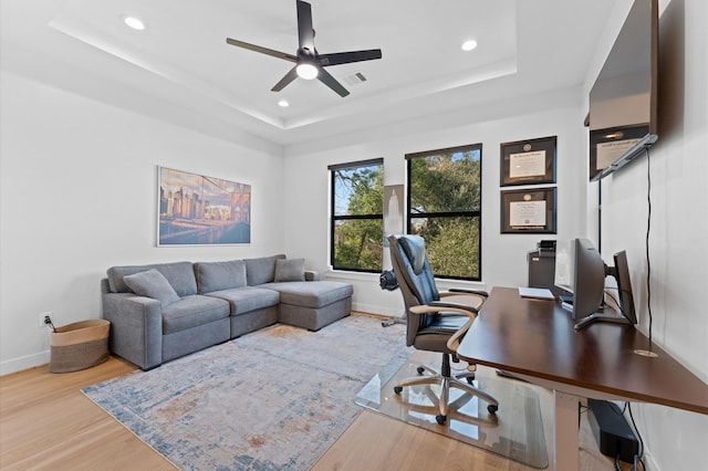 office area with recessed lighting, baseboards, a tray ceiling, and wood finished floors