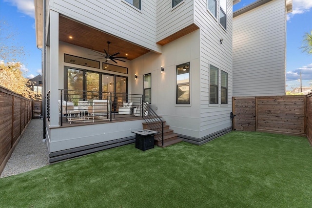 back of house featuring a lawn, a fenced backyard, and a ceiling fan