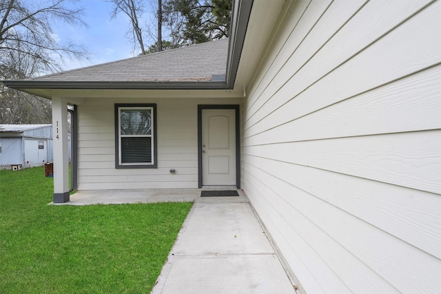 doorway to property with a yard and roof with shingles