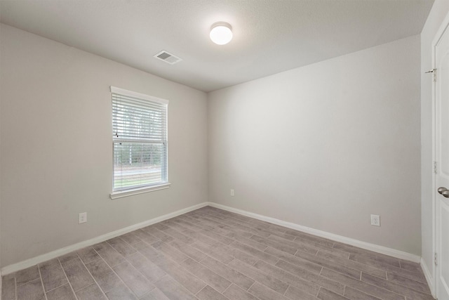 empty room featuring visible vents, baseboards, and wood finished floors