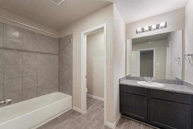 bathroom featuring wood finish floors, toilet, vanity,  shower combination, and baseboards