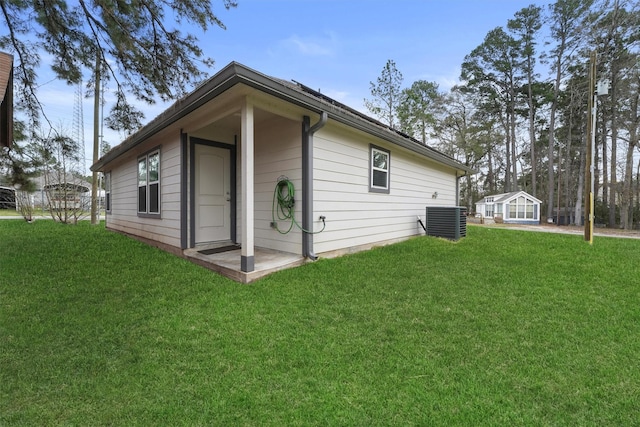 rear view of property with central AC and a lawn