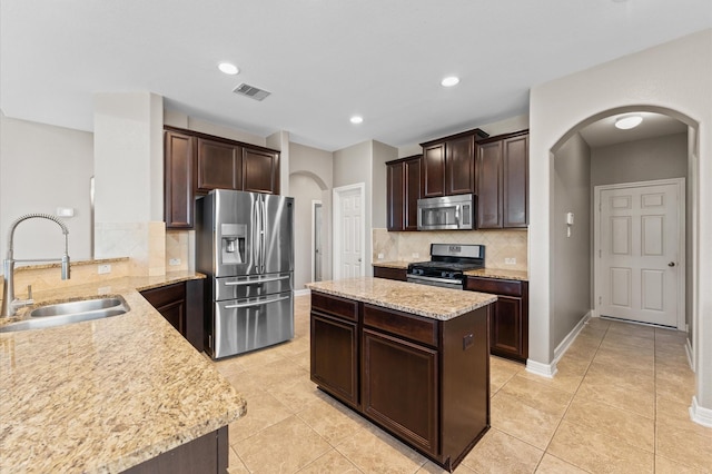 kitchen featuring arched walkways, stainless steel appliances, visible vents, a sink, and dark brown cabinetry