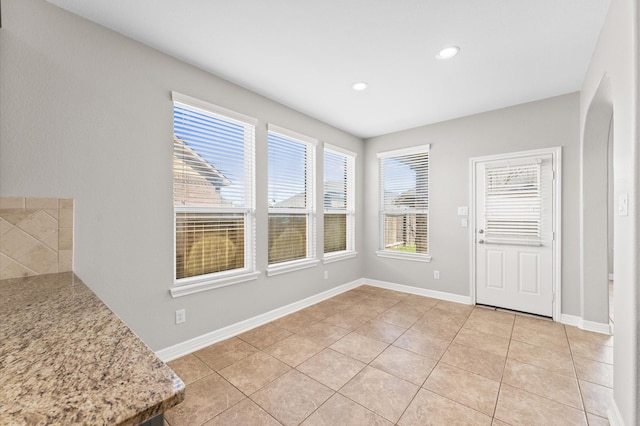 unfurnished dining area with recessed lighting, light tile patterned flooring, and baseboards