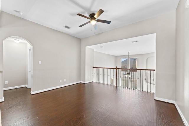 empty room with baseboards, visible vents, dark wood finished floors, and a ceiling fan