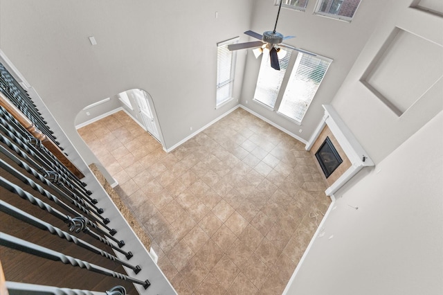 interior space featuring ceiling fan, a fireplace, a towering ceiling, and baseboards