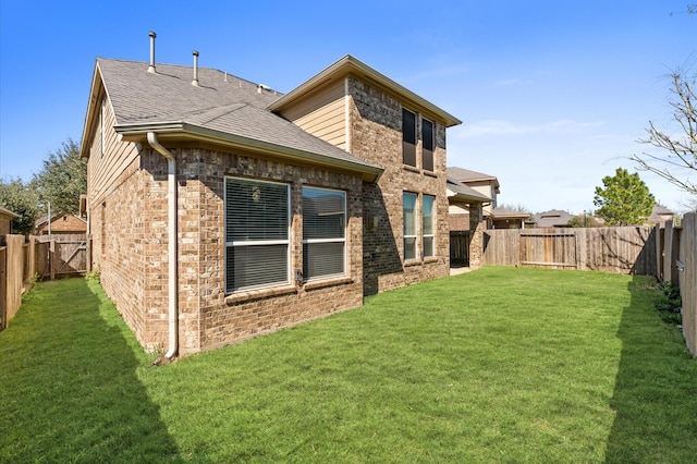 back of house with a yard, a fenced backyard, a shingled roof, and brick siding