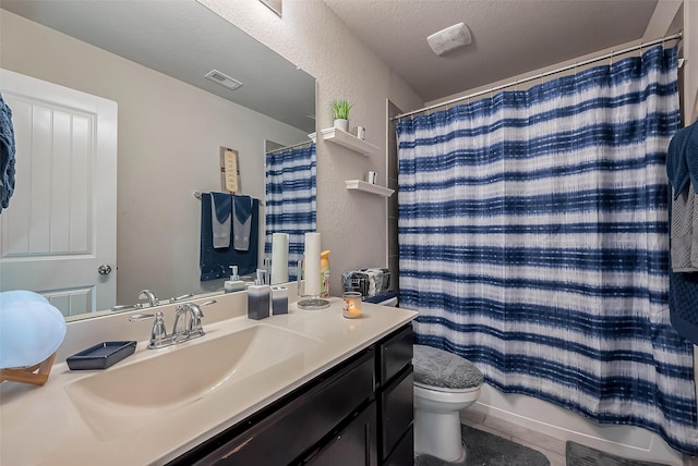 bathroom featuring visible vents, a textured wall, vanity, and toilet